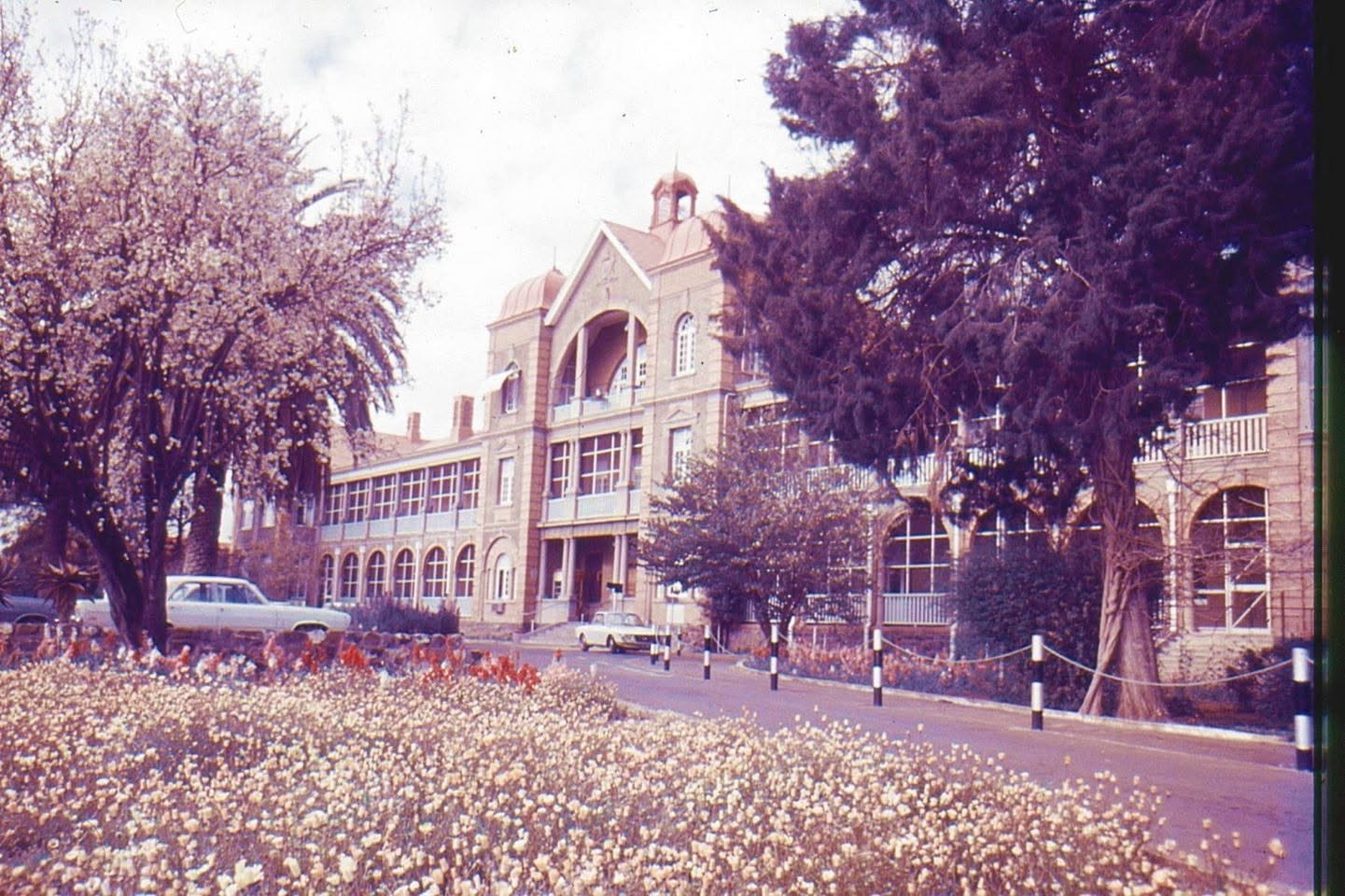 Colour photograph of Kimberley Hospital, completed in 1915, showing the main entrance, gardens and mature trees before the building was demolished in 1982.